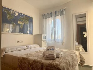 Ein Schlafzimmer mit einem Bett, einer an der Wand hängenden Karte, einem Fenster mit Vorhängen und einem Spiegel.