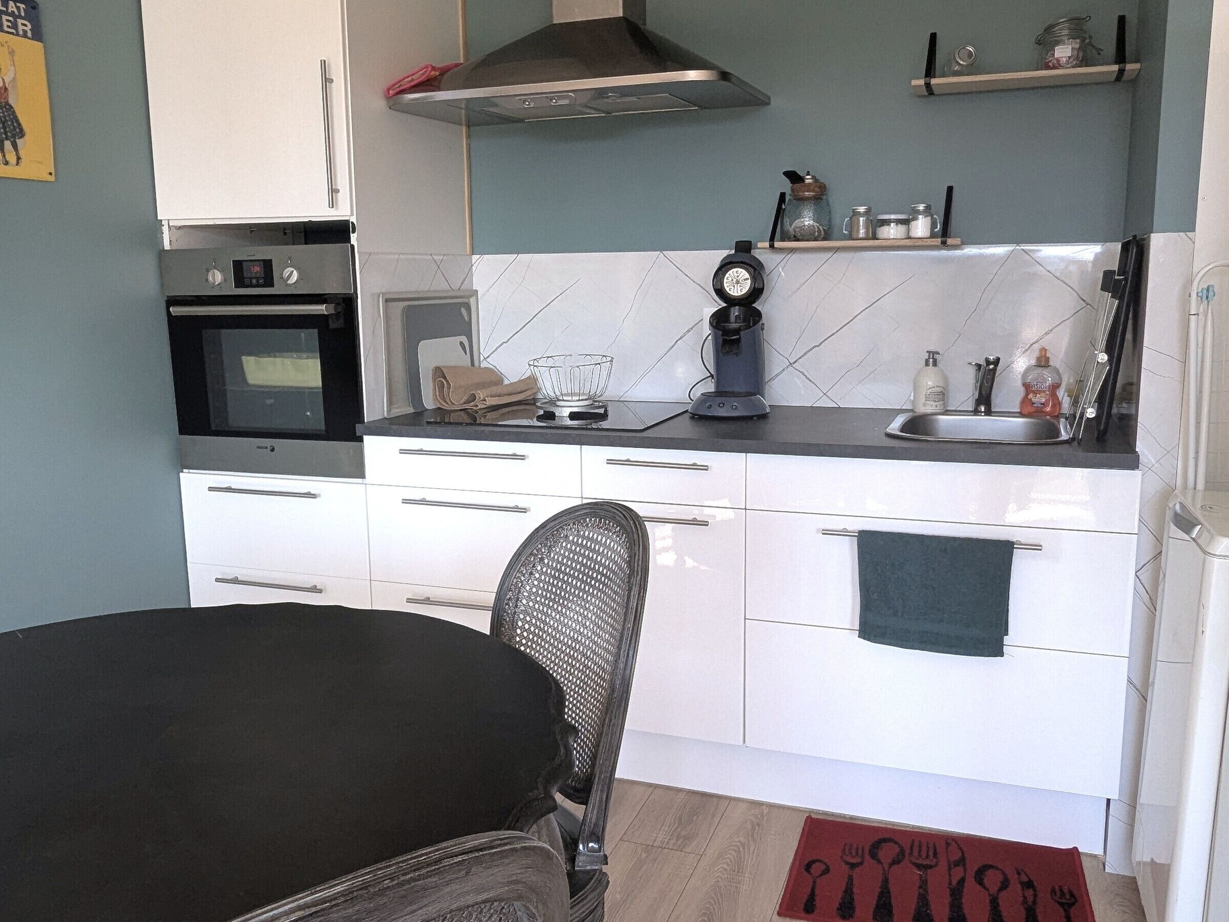 A compact kitchen with white cabinets, a stove, a microwave, and a sink.