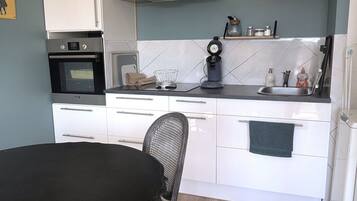 A compact kitchen with white cabinets, a stove, a microwave, and a sink.