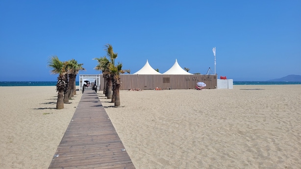 A beach with a wooden walkway leading to a white tented structure labeled "LA NNL VAGUE". - Canet-en-Roussillon: Studio for 2 with balcony (Canet-en-Roussillon)