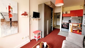A modern living room with a red carpet, a sofa, a coffee table, and a painting on the wall. - Canet-en-Roussillon: Studio for 2 with balcony (Canet-en-Roussillon)