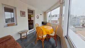 Ein Balkon mit Esstisch und Stühlen, einem kleinen Beistelltisch und einer Couch.