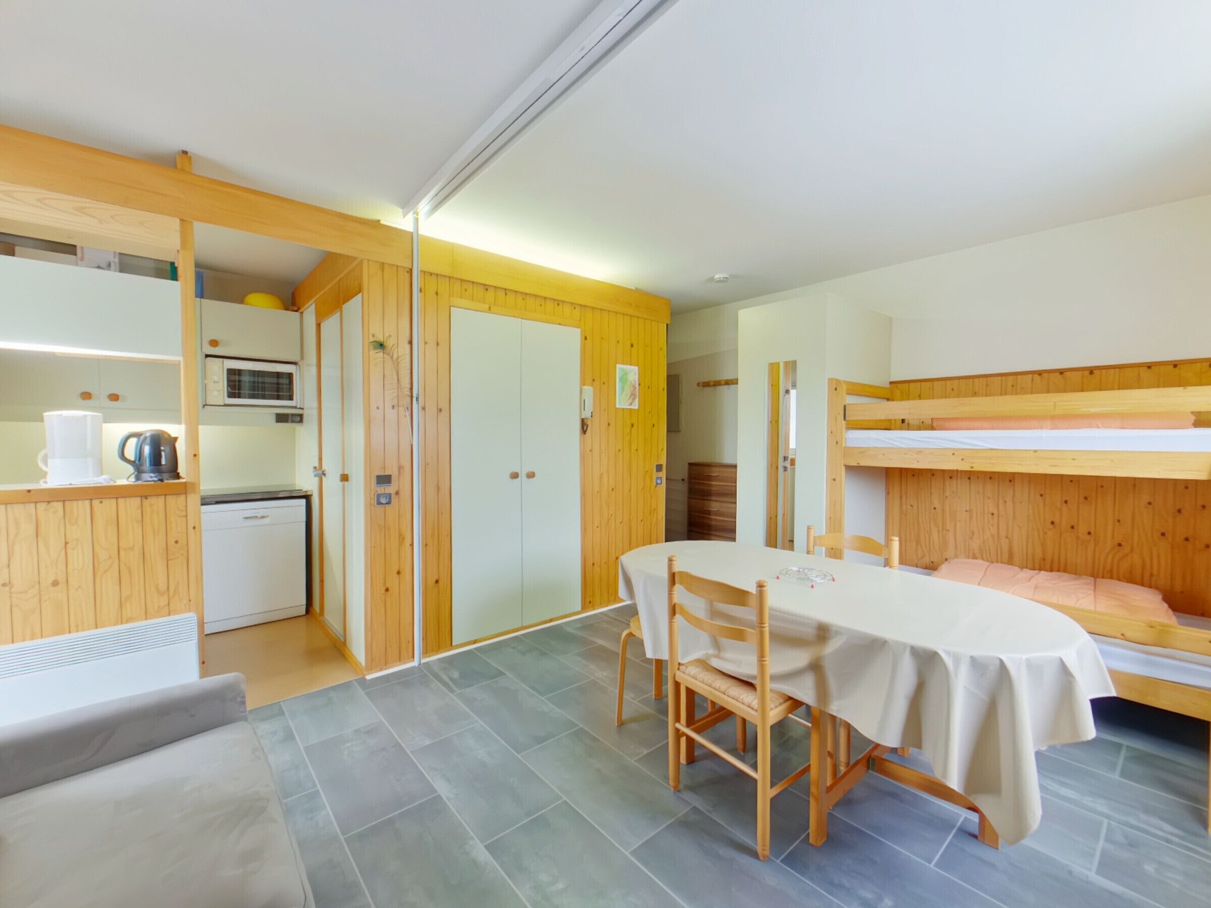 Habitación pequeña con literas, kitchenette y mesa de comedor.