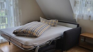 Una camera da letto con un letto, un comodino e una finestra con tende.