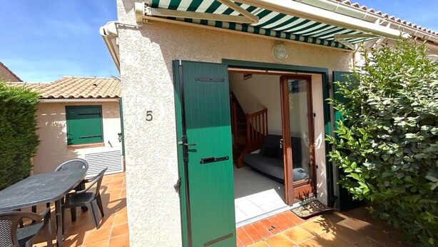 A building with a green door, a patio with a table and chairs, and a tiled roof. - 2-Bedroom Pavilion with Parking in Argelès-sur-Mer (Argelès-sur-Mer)