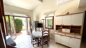 A kitchen with a dining table, chairs, a refrigerator, a TV, and a cabinet. - 2-Bedroom Pavilion with Parking in Argelès-sur-Mer (Argelès-sur-Mer)
