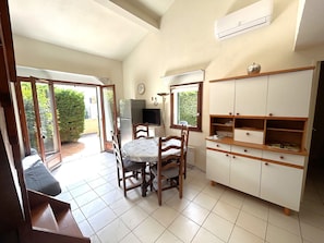 A kitchen with a dining table, chairs, a refrigerator, a TV, and a cabinet. - 2-Bedroom Pavilion with Parking in Argelès-sur-Mer (Argelès-sur-Mer)