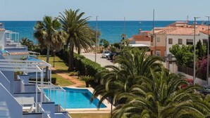 A resort with a swimming pool, palm trees, and a view of the sea. - Charming 2-Bedroom Apartment in Denia, Beach Access, Parking Included (Denia)