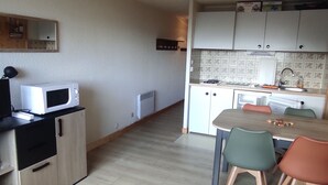 A compact kitchen with a microwave, cabinets, and a dining area with chairs. - Studio in Station Center with Free Wi-Fi (Besse-et-Saint-Anastaise-Super Besse)