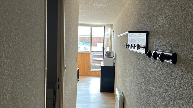 A hallway with a radiator, a wall-mounted light fixture, and a door leading to a room. - Studio in Station Center with Free Wi-Fi (Besse-et-Saint-Anastaise-Super Besse)