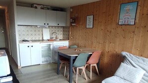 A compact kitchen with a refrigerator, a sink, and a dining area with chairs and a table. - Studio in Station Center with Free Wi-Fi (Besse-et-Saint-Anastaise-Super Besse)