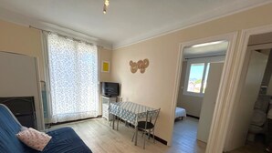 Un espacio habitable compacto con un sofá, una pequeña mesa de comedor y un televisor.