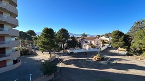 Zona residencial con cielo despejado, un área peatonal central y un edificio con varios balcones.