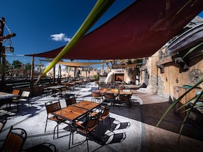An outdoor patio with tables and chairs, a large umbrella, and a stone wall. - Mobile home for 5 pers with terrace in Agde (Agde)