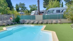 A swimming pool with a metal ladder, surrounded by green artificial grass and white lounge chairs. - Cozy mobile home with terrace for 4 people (Le Pradet)