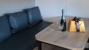 A modern room with a wooden table, a bottle of champagne, two glasses, and a gift box. - Cozy mobile home with terrace for 4 people (Le Pradet)