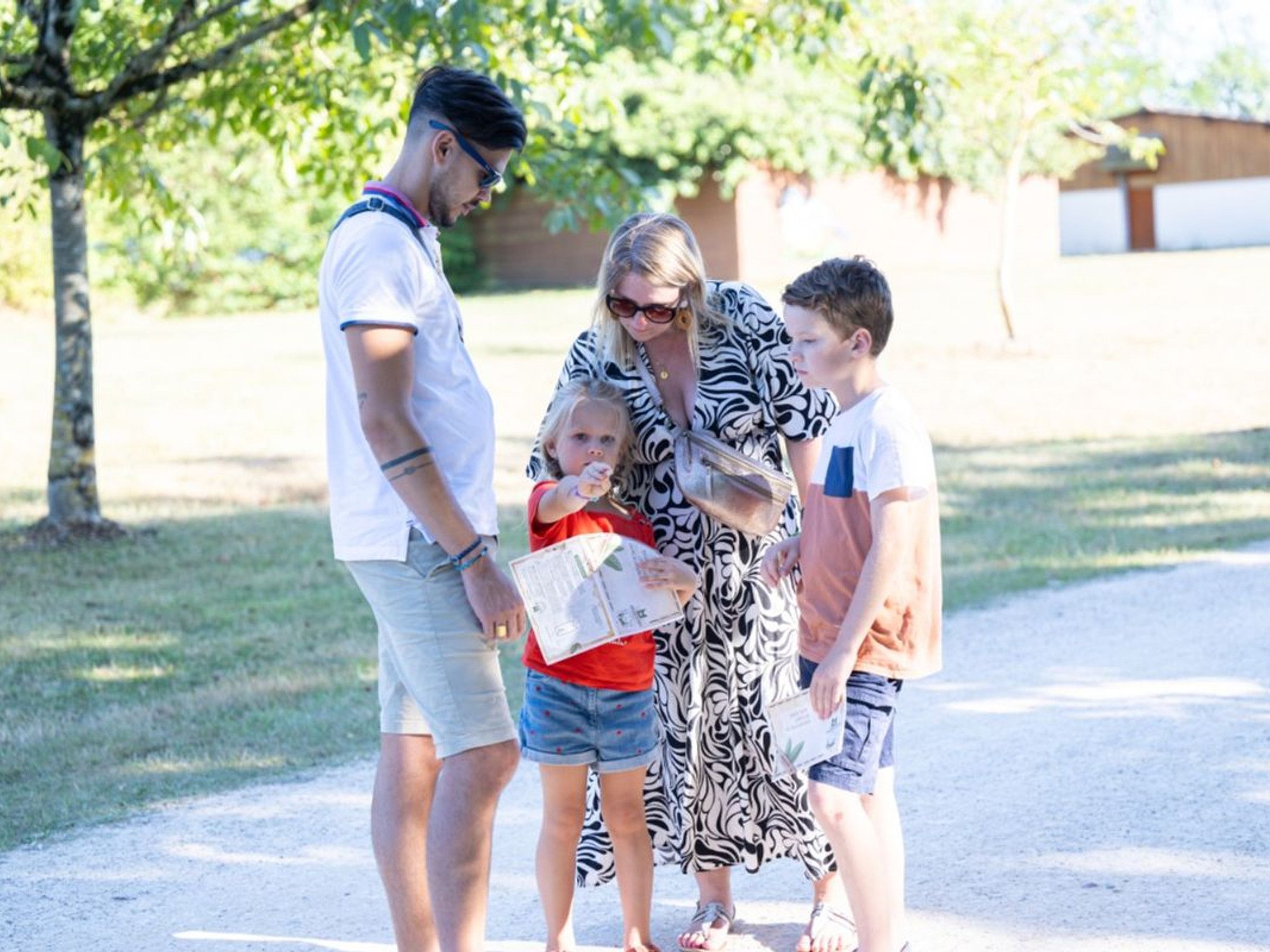 A family of four standing on a paved path in a residential area.
