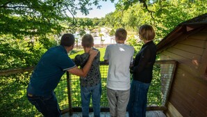 En træterrasse med gelænder i metal, med udsigt over et grønt landskab.