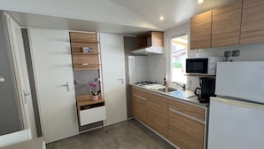 Una cocina compacta con armarios de madera, un microondas, una estufa y un refrigerador.