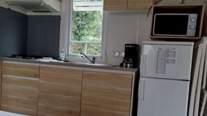Uma cozinha compacta com armários de madeira, micro-ondas e geladeira.