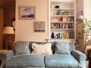 Un salon avec un canapé, une bibliothèque et une lampe.