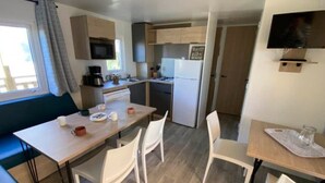 Una cucina compatta con zona pranzo, forno a microonde, macchina del caffè e TV a parete.
