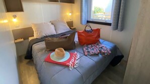 Una camera da letto con un letto, un comodino, una finestra con tende e una mensola a parete.