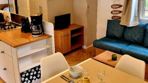 Una zona d'estar acollidora amb una taula de fusta, un sofà, una cafetera i una televisió.