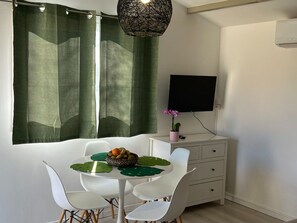 Quarto moderno com mesa de jantar, cadeiras, TV e armário.