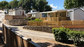 Filas de casas móviles con paredes de piedra y cercas de madera, alineadas a lo largo de un camino de grava.