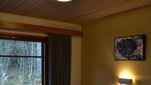 A hotel room with two beds, a window with curtains, a wall-mounted light, and a painting. - Saimaa Style Spa Chalet (Imatra)