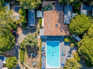 An aerial view of a residential area with a swimming pool, adjacent houses, and a red car parked on the street. - Mobile home with terrace, 3 bedrooms, for 6 people (Rivedoux-Plage)