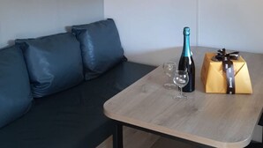 A modern room with a wooden table, a bottle of champagne, two wine glasses, and a gift box. - Mobile Home for 4 with Terrace in Le Pradet (Le Pradet)