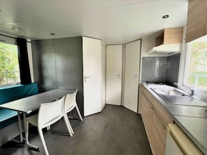 A compact kitchen with a dining area, a window, and a built-in stove. - Mobile home for 4 with terrace in Espelette (Espelette)