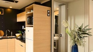 A modern kitchen with wooden cabinets, a black countertop, and a blue vase with flowers on a table. - Spacious chalet with terrace for 5 people (Nibelle)