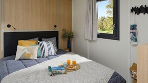 A modern bedroom with a bed, bedside table, and a window with curtains. - Spacious chalet with terrace for 5 people (Nibelle)