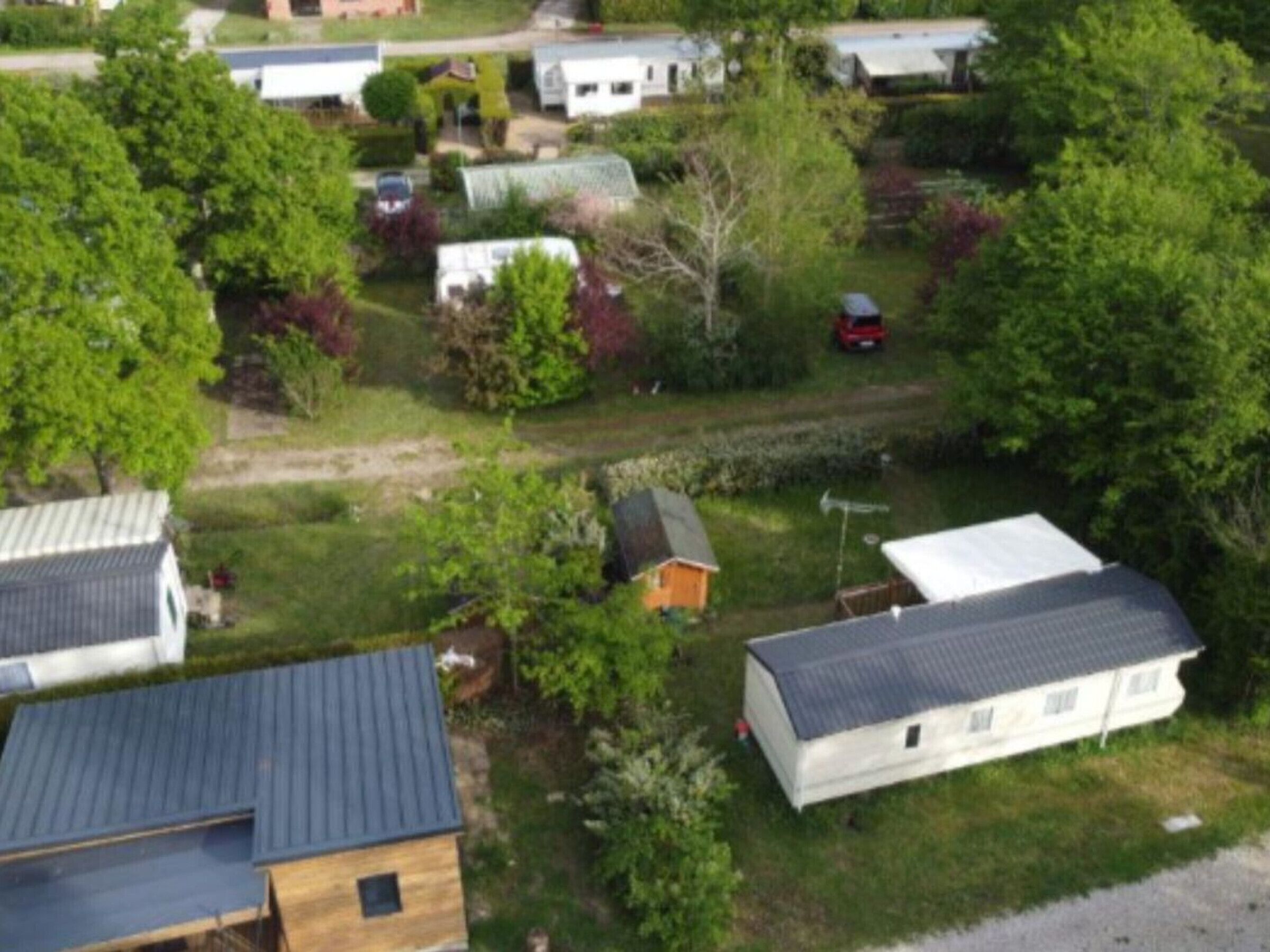 Un vecindario residencial con varias casas, algunas con garajes adjuntos, rodeado de vegetación y árboles.