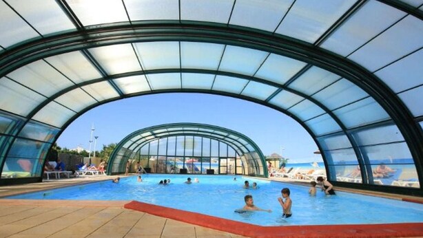 Una piscina interior con techo de cristal y suelo de baldosas.