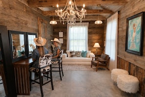 A rustic interior with wooden walls, a chandelier, a sofa, and a dining area with chairs.