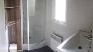 Un bagno con doccia, una finestra e un termosifone.