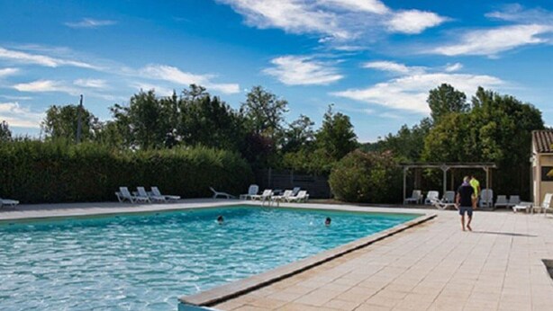 Una piscina con acqua cristallina, circondata da sdraio e una zona coperta.