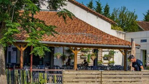 Un edificio con tetto in tegole, zona salotto all'aperto e recinzione in legno.