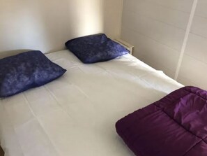 A bed with white bedding and two dark blue pillows. - Functional Mobile Home in Jard-sur-Mer, 3 Bedrooms, Sleeps 6 (Jard-sur-Mer)