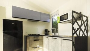 A compact kitchen with a black refrigerator, a microwave, and a coffee maker. - Mobile home with terrace in Saint-Coulomb (Saint-Coulomb)