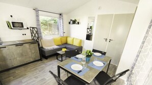 A compact living space with a dining area, kitchenette, and a sofa with yellow cushions. - Mobile home with terrace in Saint-Coulomb (Saint-Coulomb)