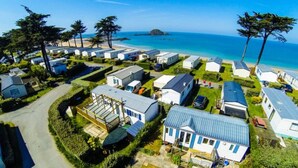 A mobile home park with several single-story homes, a road, and a beach in the background. - Mobile home with terrace in Saint-Coulomb (Saint-Coulomb)