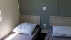 A room with two beds, each with a wooden headboard and white bedding. There is a small bedside table between the beds. - Comfortable Mobile Home with Terrace in Cavaillon (Cavaillon)