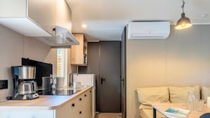 A compact kitchen with a coffee maker, microwave, and sink. There is a dining area with a table and chairs, and a sofa. - Mobile home 4 pers with terrace in Rivedoux-Plage (Rivedoux-Plage)
