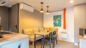 A modern, compact living space with a kitchenette, dining area, and a large window with a view of greenery. - Mobile home 4 pers with terrace in Rivedoux-Plage (Rivedoux-Plage)