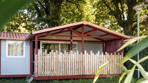 A small, single-story building with a red roof and a wooden fence. - 3-bedroom mobile home with terrace in Espelette (Espelette)